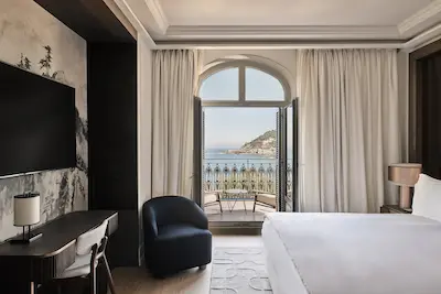 Habitación de hotel elegante con un amplio balcón y vistas a la playa.