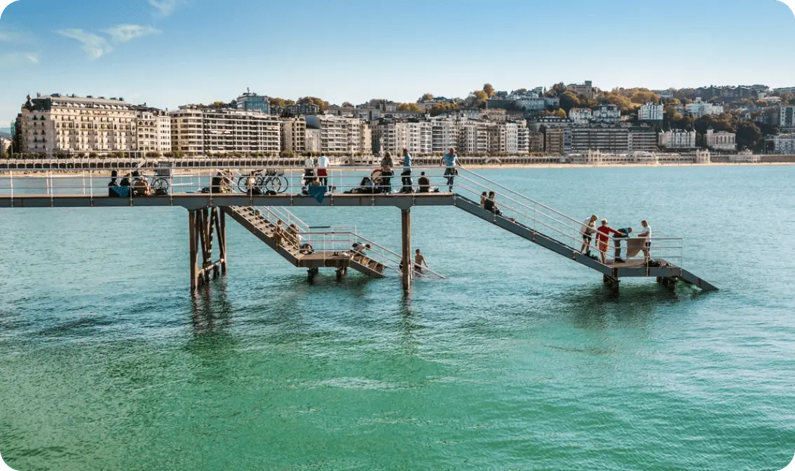 Gente bañándose en las escaleras de acceso al mar.