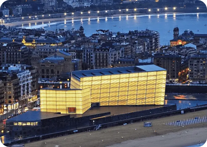 Vista nocturna del Kursaal iluminado desde la playa.