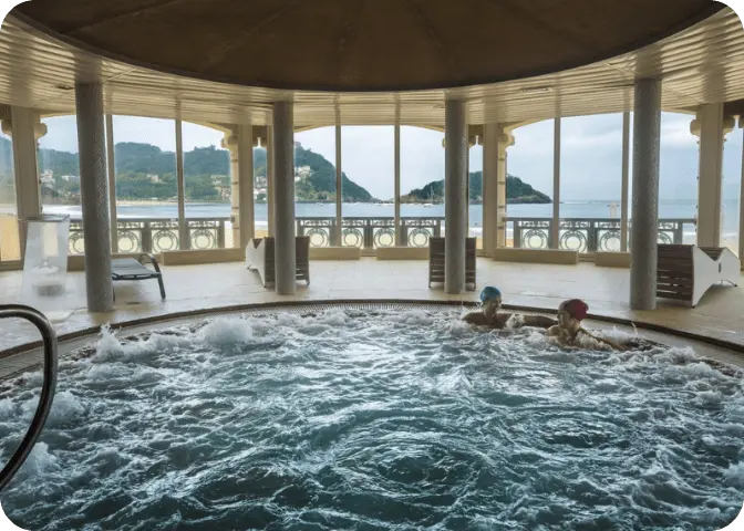 Dos personas disfrutando del jacuzzi de La Perla con vistas a la playa.