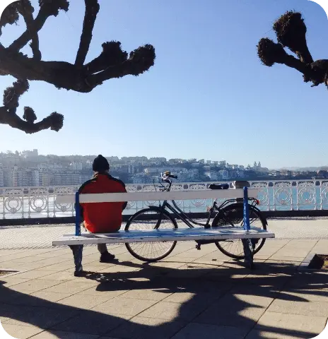 Hombre descansando junto a su bicicleta con vistas a la playa y la ciudad al fondo